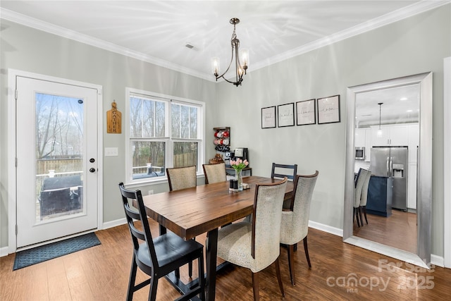 dining area featuring hardwood / wood-style floors, ornamental molding, and a chandelier