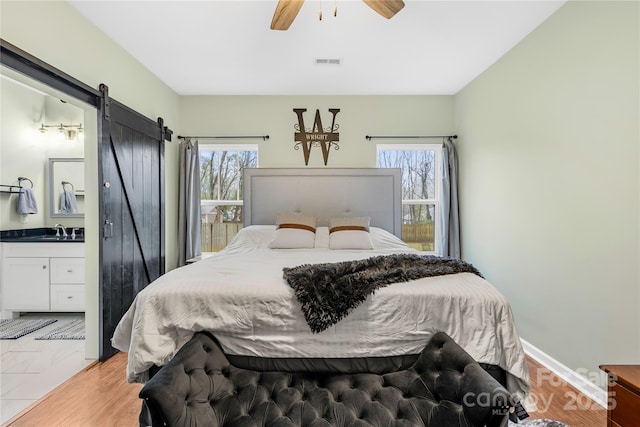 bedroom with multiple windows, sink, connected bathroom, and a barn door