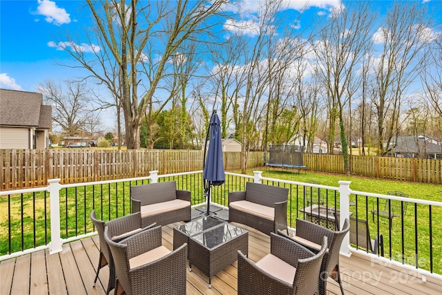 wooden terrace featuring an outdoor hangout area, a trampoline, and a lawn