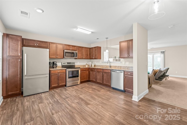 kitchen with pendant lighting, sink, hardwood / wood-style flooring, and stainless steel appliances