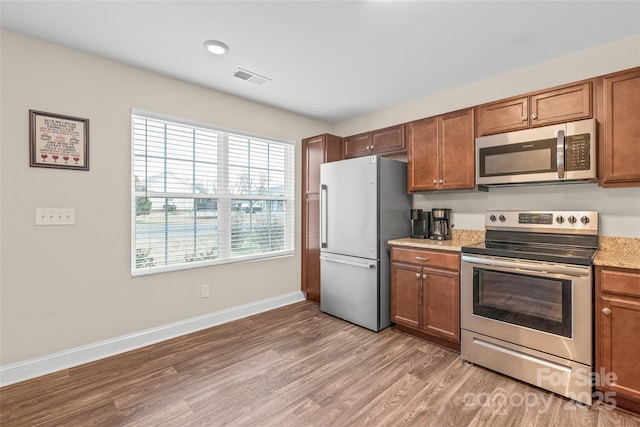 kitchen with visible vents, baseboards, light wood-style floors, appliances with stainless steel finishes, and brown cabinets