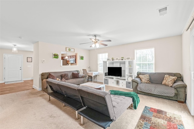 living room with a wealth of natural light, visible vents, baseboards, and ceiling fan