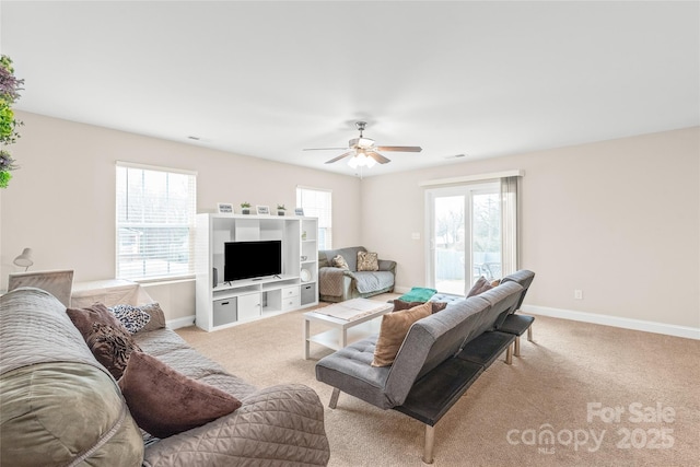 living area featuring baseboards, light colored carpet, a healthy amount of sunlight, and ceiling fan