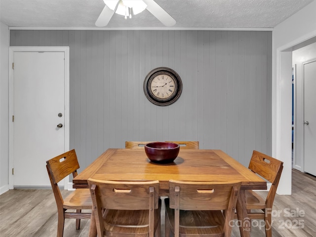 dining space with ceiling fan, a textured ceiling, and light wood-type flooring