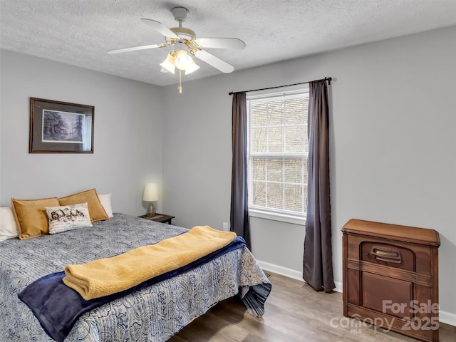 bedroom featuring ceiling fan, a textured ceiling, and light wood-type flooring