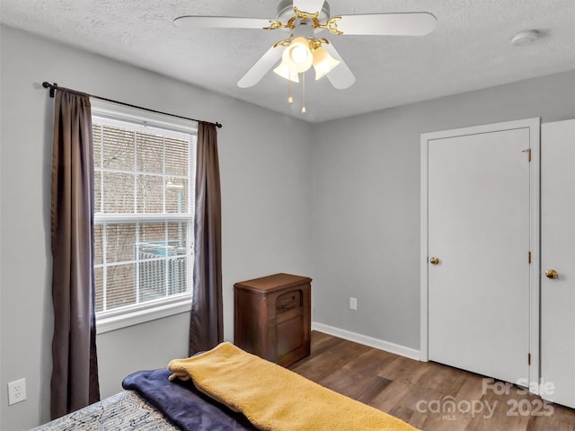 bedroom with ceiling fan, a textured ceiling, and dark hardwood / wood-style flooring