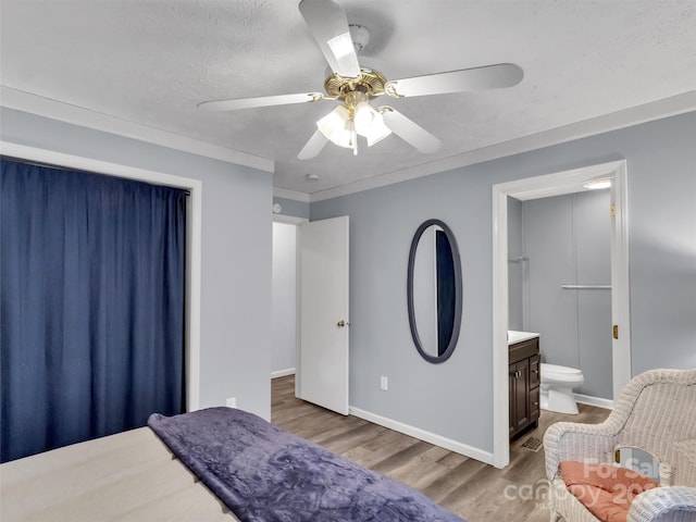 bedroom featuring crown molding, light hardwood / wood-style flooring, ceiling fan, connected bathroom, and a textured ceiling