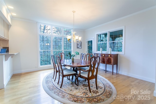 dining room with light wood-style flooring, a notable chandelier, and ornamental molding