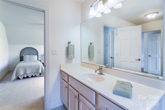 ensuite bathroom featuring vanity, baseboards, vaulted ceiling, and ensuite bathroom