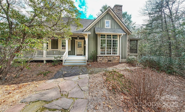 view of front of property featuring crawl space, a chimney, roof with shingles, board and batten siding, and a porch