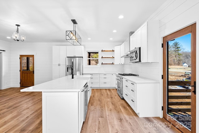 kitchen featuring pendant lighting, white cabinetry, appliances with stainless steel finishes, and a center island with sink