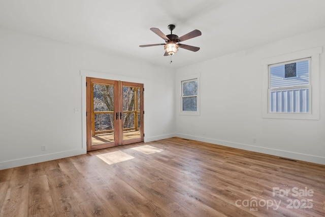 spare room with french doors, ceiling fan, a healthy amount of sunlight, and light wood-type flooring