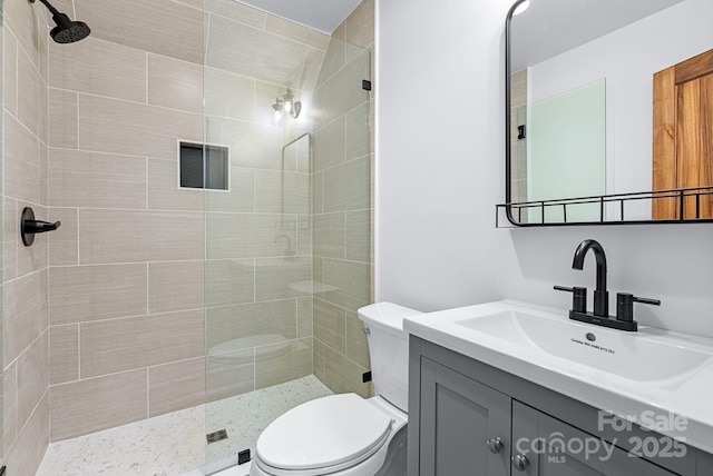 bathroom featuring vanity, toilet, and a tile shower