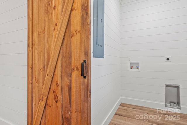 laundry area featuring wooden walls, electric panel, hookup for a washing machine, and electric dryer hookup