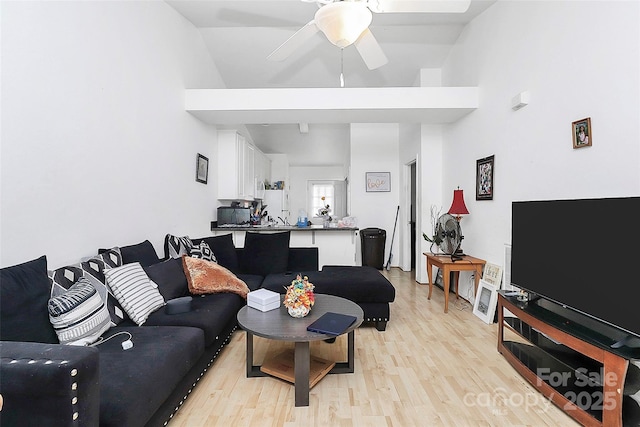 living room featuring a towering ceiling, ceiling fan, and light hardwood / wood-style flooring