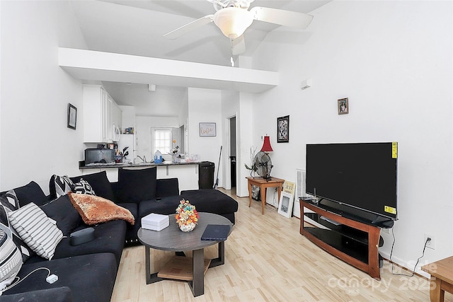 living room with ceiling fan, lofted ceiling, and light wood-type flooring