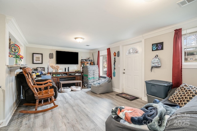 living area featuring baseboards, wood finished floors, visible vents, and crown molding