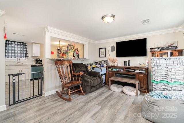 living room with ornamental molding, baseboards, visible vents, and light wood finished floors