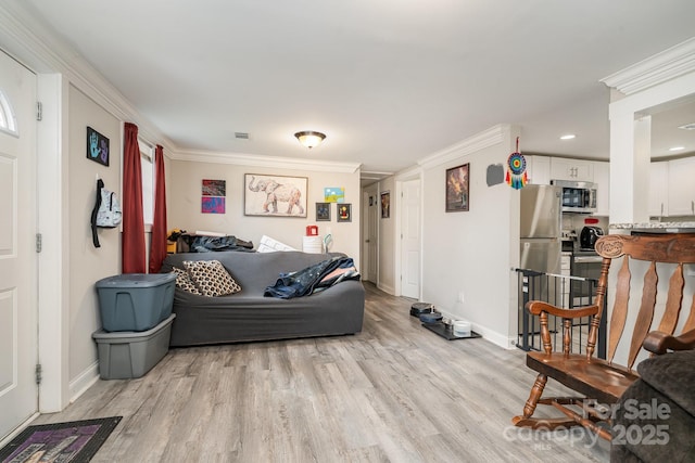 living room with light wood-style flooring, visible vents, baseboards, and crown molding