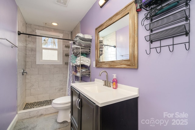 full bath with visible vents, a tile shower, vanity, and toilet