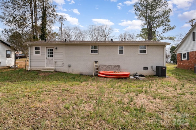 back of property featuring central air condition unit, crawl space, a lawn, and brick siding