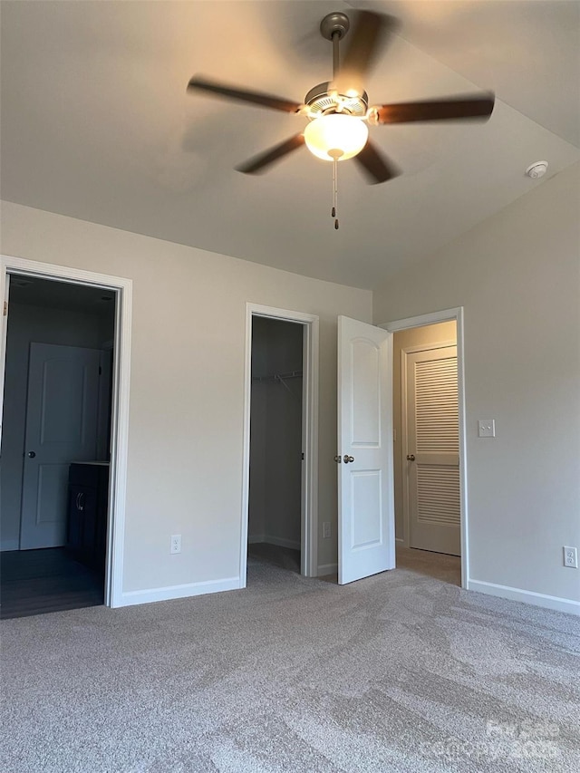 unfurnished bedroom featuring ceiling fan, ensuite bathroom, carpet flooring, and a spacious closet