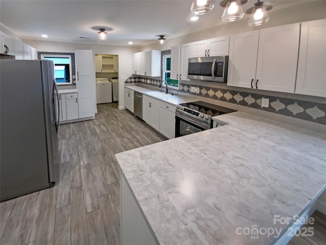 kitchen with white cabinetry, sink, stainless steel appliances, and washing machine and clothes dryer