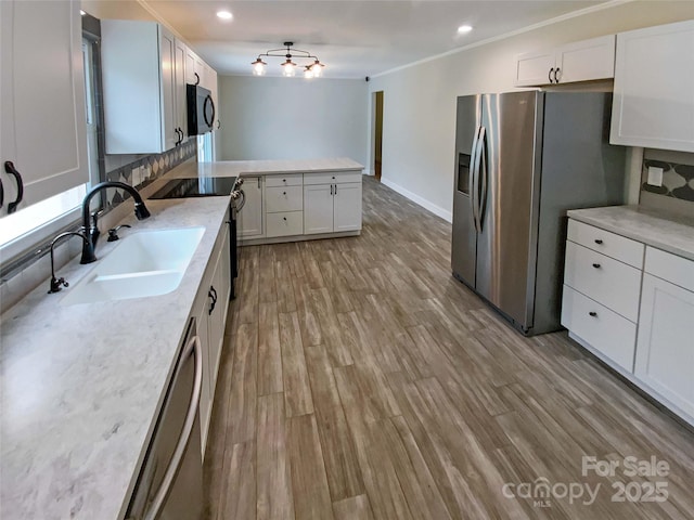 kitchen with stainless steel appliances, sink, light hardwood / wood-style flooring, and white cabinets