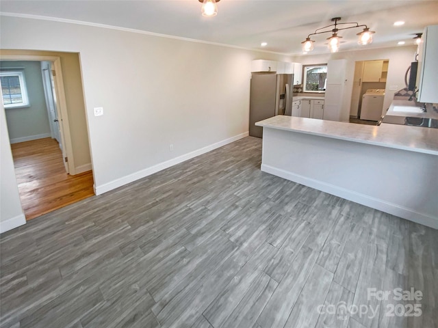 kitchen featuring white cabinetry, stainless steel fridge, hardwood / wood-style flooring, ornamental molding, and kitchen peninsula