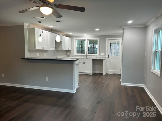 kitchen featuring visible vents, ornamental molding, dark wood-type flooring, a peninsula, and white cabinetry