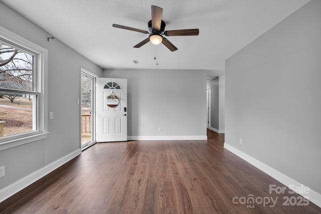 interior space with ceiling fan, a textured ceiling, and dark hardwood / wood-style flooring