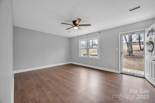 empty room featuring ceiling fan, dark hardwood / wood-style floors, and a textured ceiling