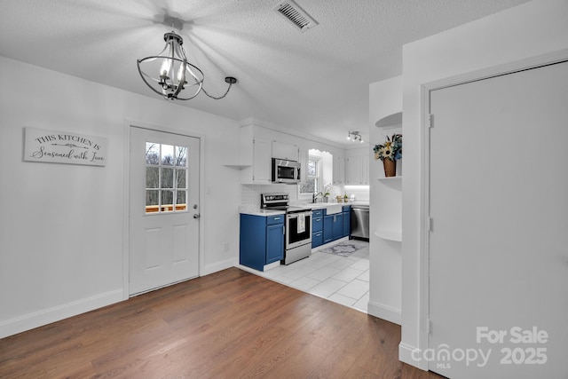 kitchen with pendant lighting, light hardwood / wood-style flooring, stainless steel appliances, white cabinets, and blue cabinets