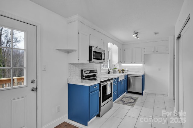 kitchen featuring white cabinetry, stainless steel appliances, blue cabinets, and backsplash