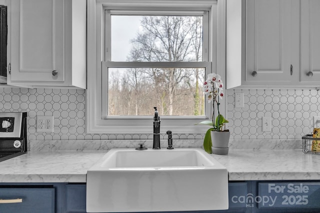 kitchen featuring white cabinetry, sink, tasteful backsplash, and light stone countertops