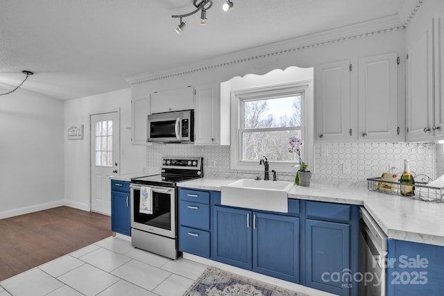 kitchen with sink, white cabinetry, stainless steel appliances, tasteful backsplash, and blue cabinets