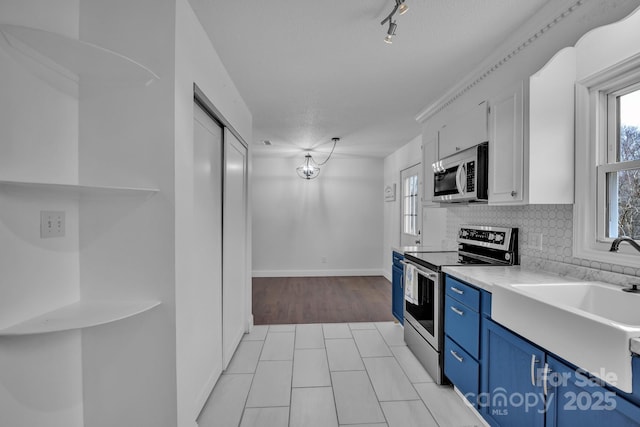 kitchen featuring sink, blue cabinetry, backsplash, stainless steel appliances, and white cabinets