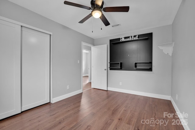 unfurnished bedroom with wood-type flooring, ceiling fan, and a closet