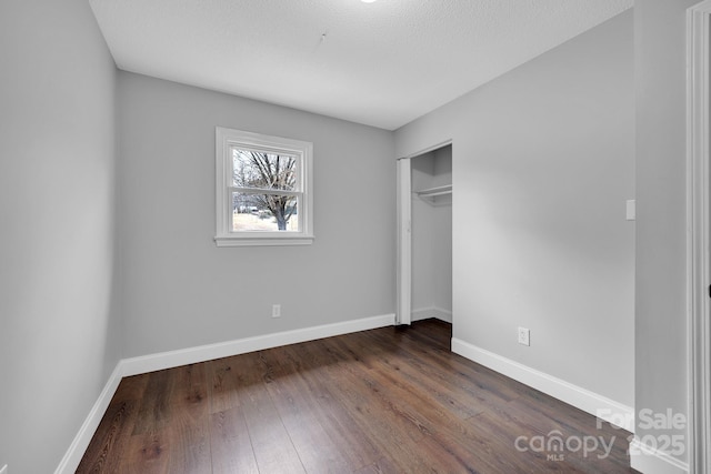 unfurnished bedroom featuring dark wood-type flooring, a closet, and a textured ceiling