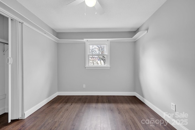 empty room with ceiling fan, dark wood-type flooring, and a textured ceiling