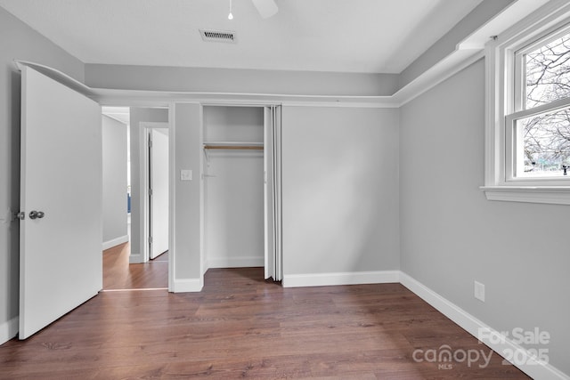 unfurnished bedroom featuring ceiling fan, dark hardwood / wood-style flooring, and a closet