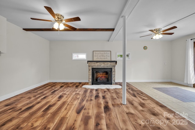 unfurnished living room with beam ceiling, ceiling fan, hardwood / wood-style floors, and a fireplace