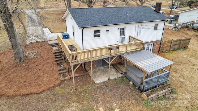 rear view of property with a wooden deck, a hot tub, and a patio