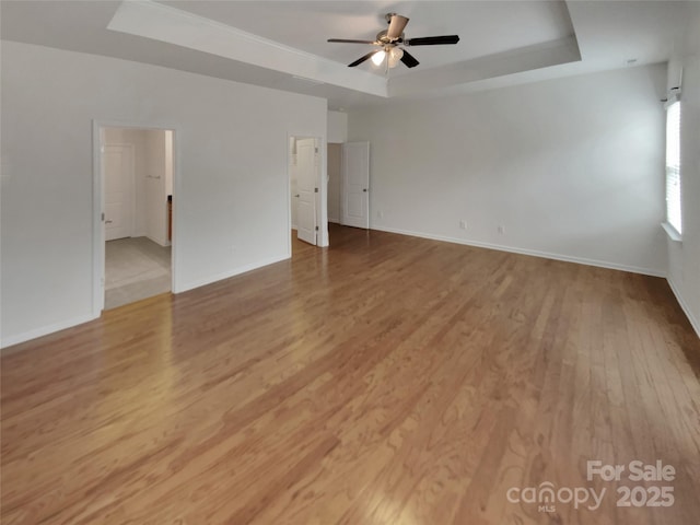 unfurnished room with light hardwood / wood-style flooring, a raised ceiling, and ceiling fan