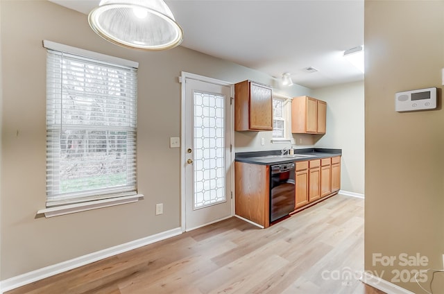 kitchen featuring a healthy amount of sunlight, sink, black dishwasher, and light wood-type flooring