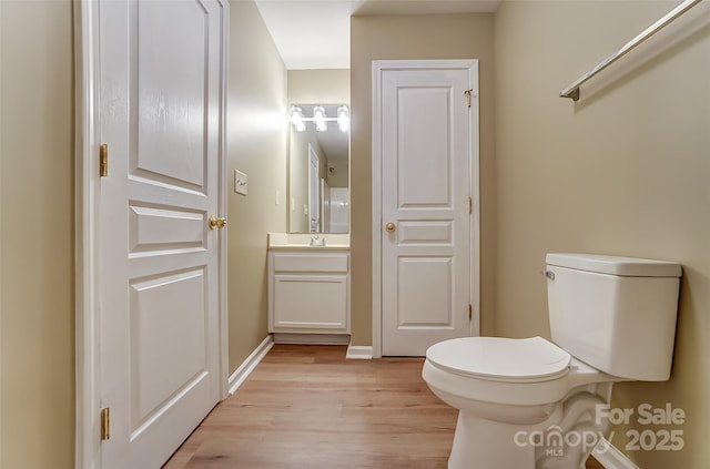 bathroom featuring vanity, wood-type flooring, and toilet