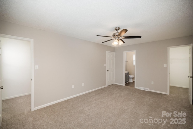 unfurnished bedroom featuring a walk in closet, carpet floors, a textured ceiling, and a closet