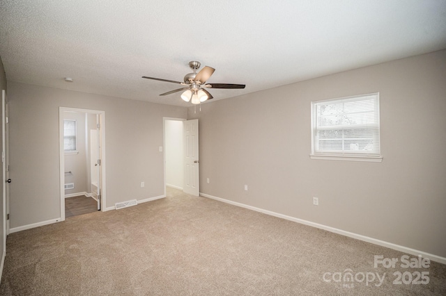 unfurnished bedroom with ceiling fan, carpet, a textured ceiling, and ensuite bath