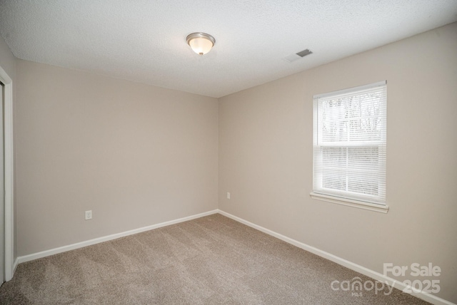 carpeted spare room with a textured ceiling