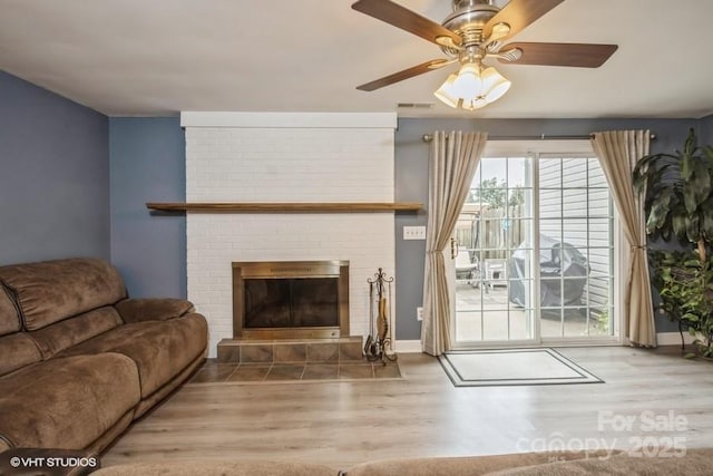 living room featuring hardwood / wood-style floors, a brick fireplace, and ceiling fan